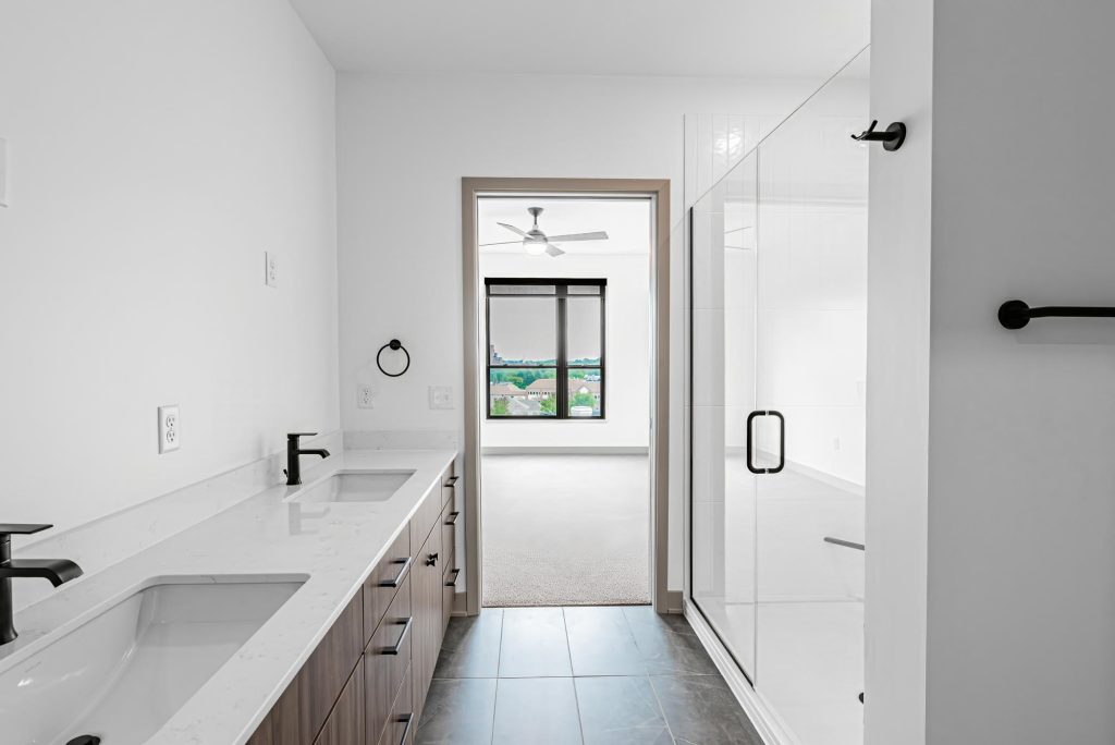 Bathroom with double vanity, quartz countertop, and glass shower