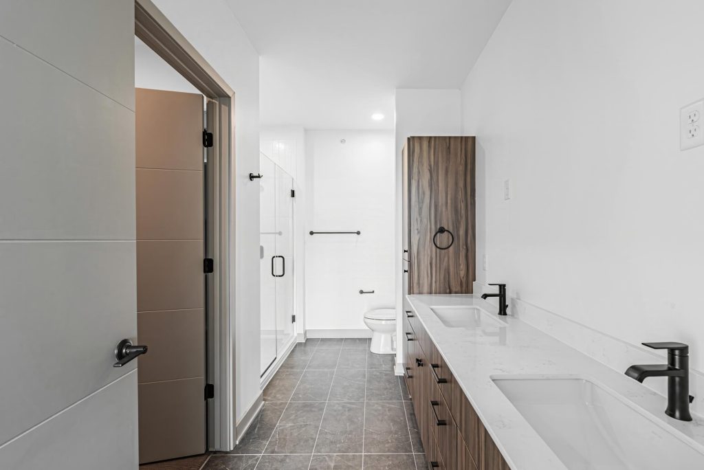 Modern bathroom with double vanity, quartz countertops, and glass shower