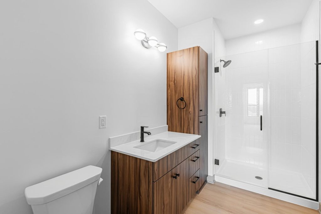 Bathroom with wood vanity, quartz countertop, and glass shower enclosure