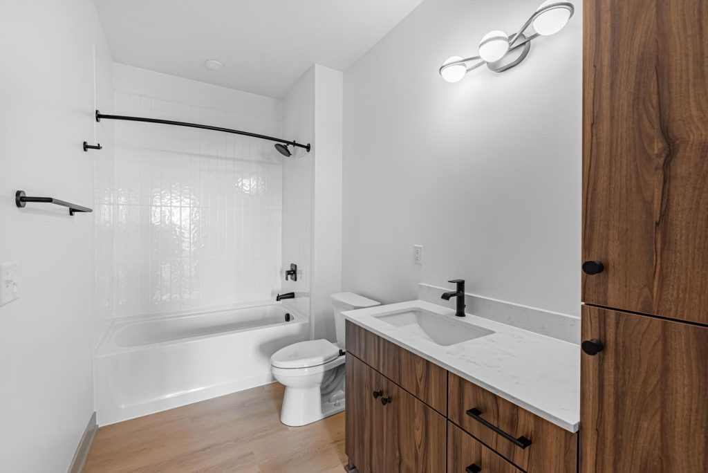 Bathroom with wood vanity, bathtub, and modern fixtures