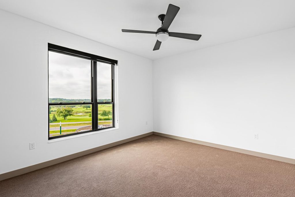 Bedroom with carpet flooring, ceiling fan, and large window with city view