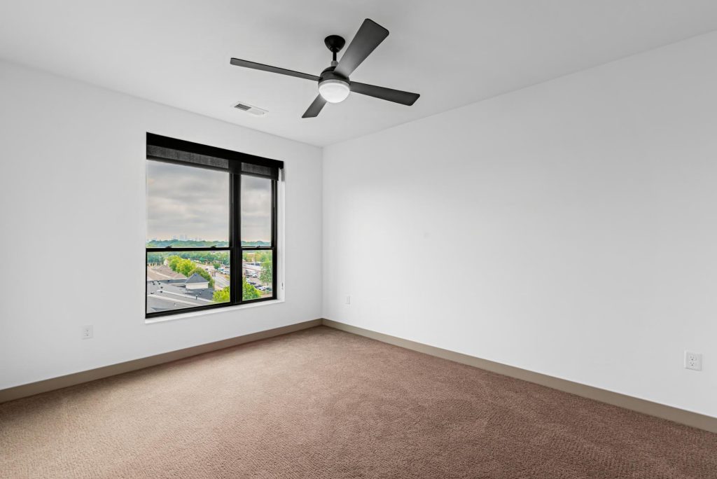 Bedroom with carpet flooring, ceiling fan, and city view window