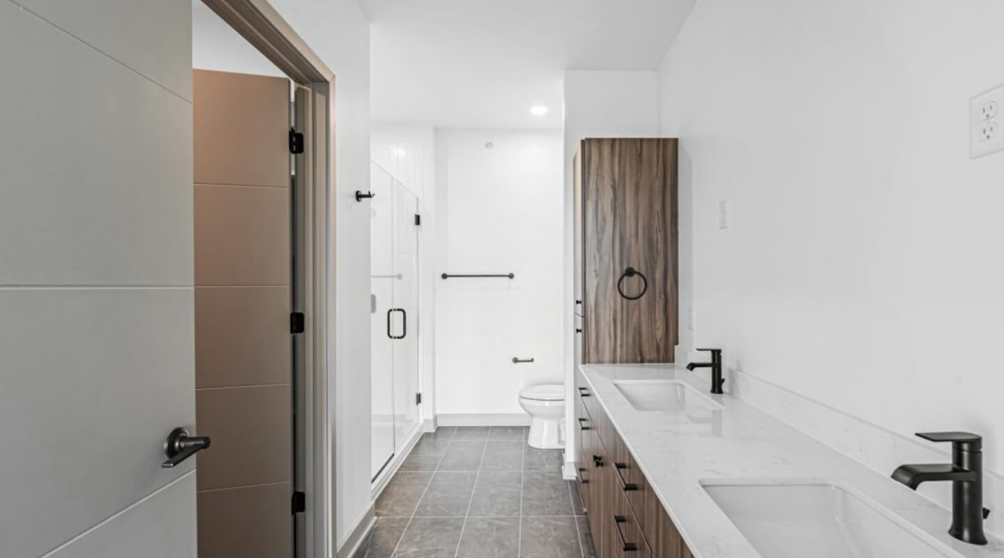 Modern bathroom at The Winn at Golden Valley featuring a double vanity and glass-enclosed shower