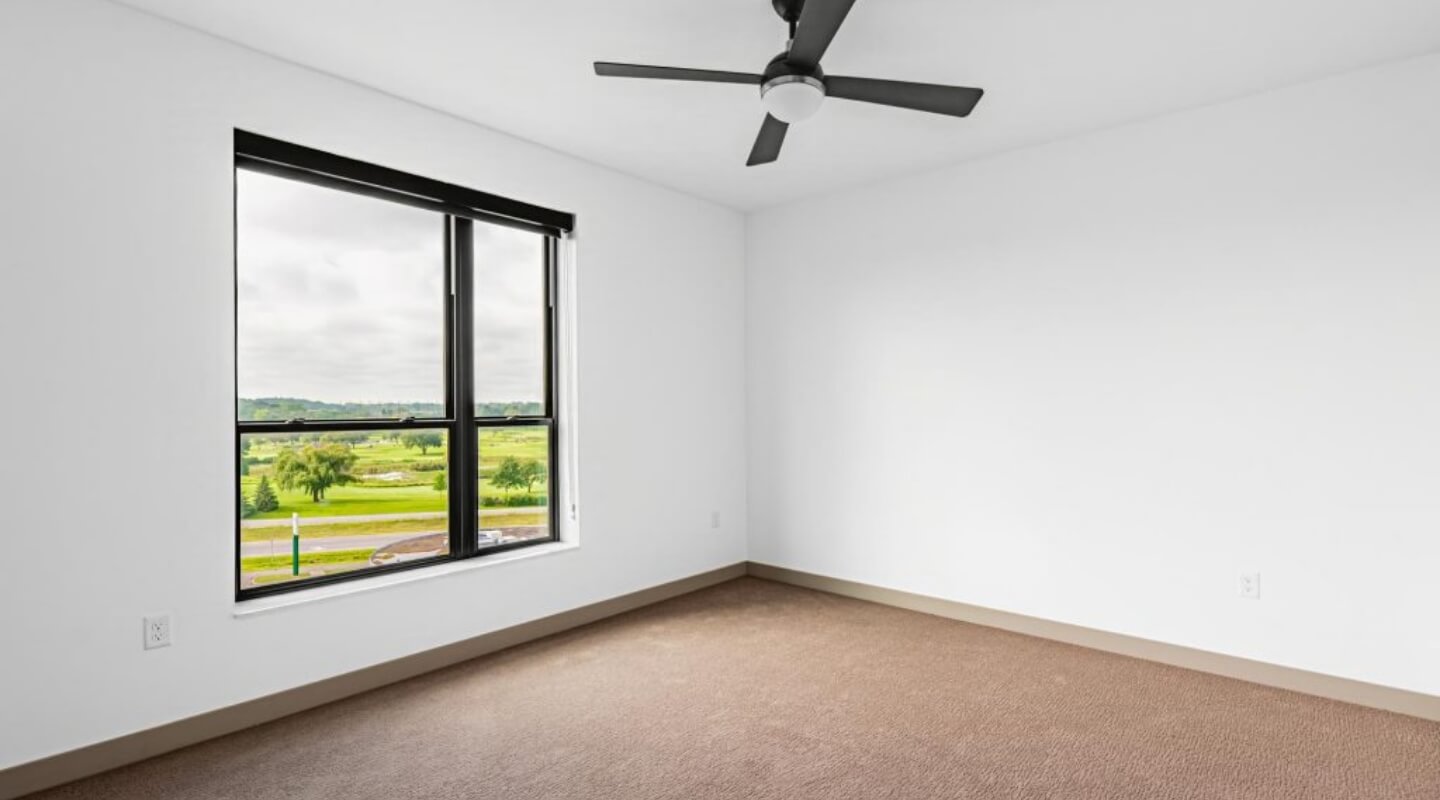 Bedroom at The Winn at Golden Valley with large window and carpet flooring