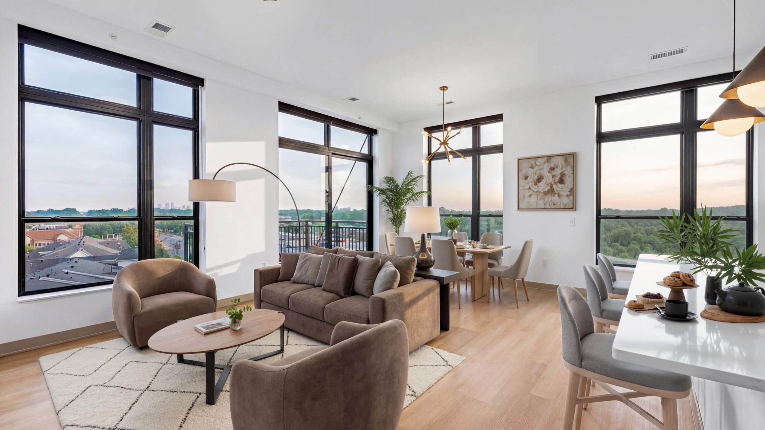 Apartment living and dining area with open floor plan, large windows, balcony view, and modern furnishings