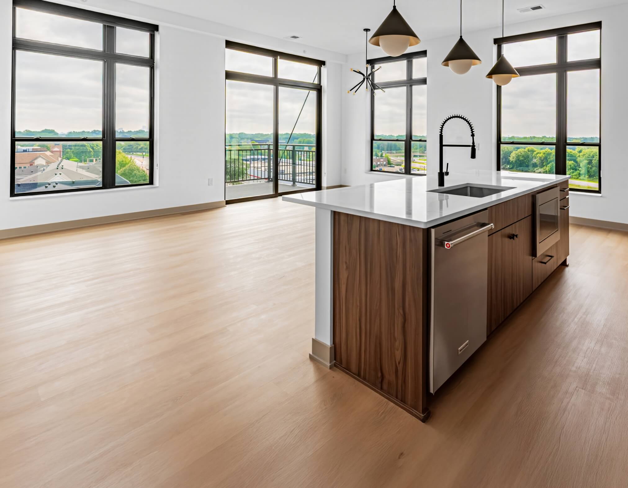 Signature Collection apartment interior with open kitchen island, wood cabinetry, large windows, and balcony view