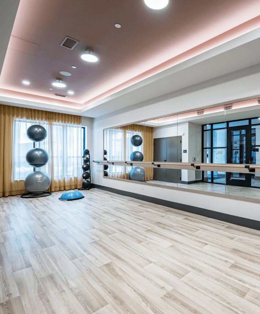 yoga studio within a fitness room, with a large mirror and open floor.